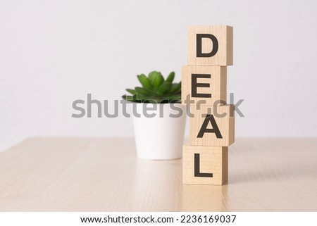 word DEAL with wood building blocks, light green background. front view.