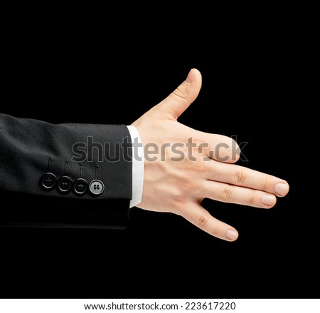 Caucasian male hand in a business suit, showing the dog gesture sign, low-key lighting composition, isolated over the black background