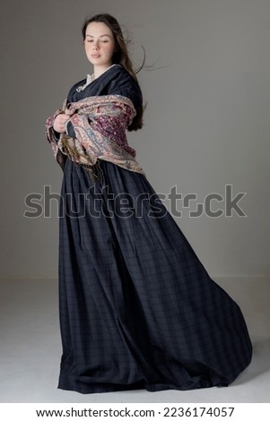 A young Victorian woman wearing a bluegrey cotton dress with a paisley shawl Royalty-Free Stock Photo #2236174057