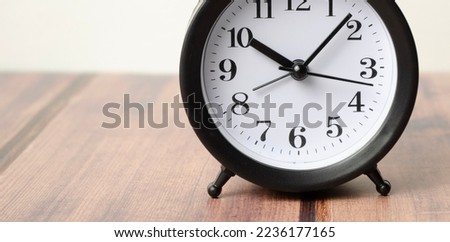Old Black vintage alarm clock on wooden table on blur background