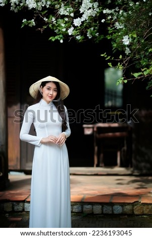 Ho Chi Minh city, Viet Nam: Ao Dai is traditional dress of vietnam, beautiful vietnamese woman in white Ao Dai dress in the park Royalty-Free Stock Photo #2236193045
