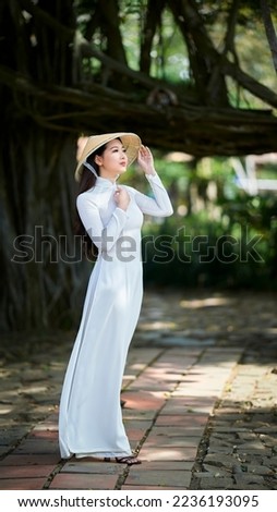 Ho Chi Minh city, Viet Nam: Ao Dai is traditional dress of vietnam, beautiful vietnamese woman in white Ao Dai dress in the park Royalty-Free Stock Photo #2236193095