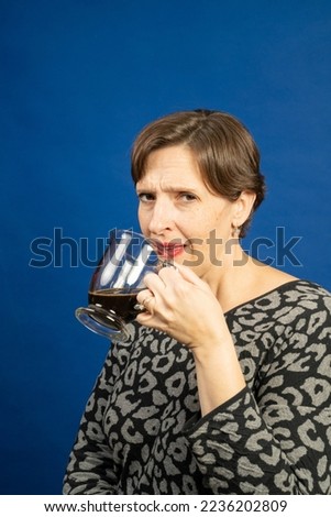 Woman enjoying a cup of black coffee. High quality studio photo was taken on a blue background.
