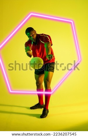 Illuminated hexagon over african american male rugby player throwing ball on green background. Copy space, composite, sport, competition, shape, playing, match and abstract concept.