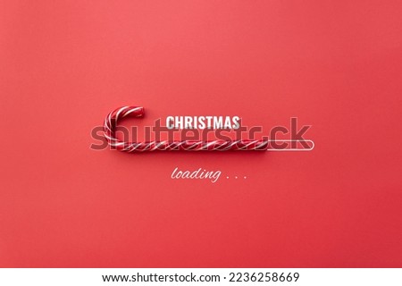 Striped candy cane and lettering Christmas loading on red background. Concept of waiting for seasonal holidays. Copy space, selective focus Royalty-Free Stock Photo #2236258669