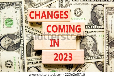 Changes coming in 2023 symbol. Concept word Changes coming in 2023 on wooden blocks. Beautiful background from dollar bills. Business and changes coming in 2023 concept. Copy space.