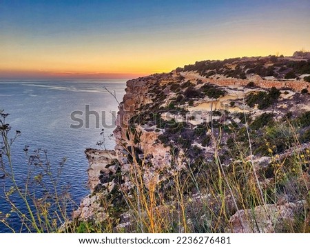 Beautiful landscape with blue sea and rocky shore. Tropical beach with ocean and rocky cape in island. Sun beyond the headland with glowing marsala toned rocks in the foreground. Beauty world