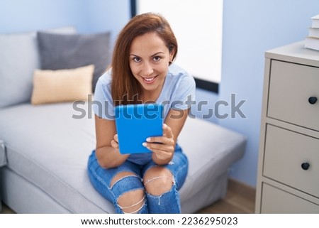 Young woman using touchpad sitting on sofa at home