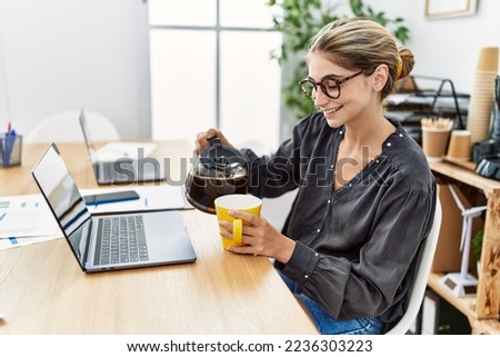 Young caucasian woman drinking coffee working at office