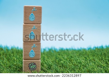 water saving icons on wooden block cubes on background with grass and sky. Environment concept for world water day