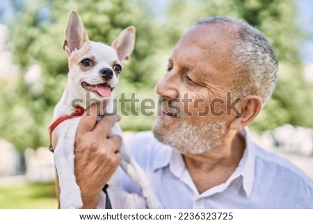 Senior man smiling confident hugging chihuahua at park