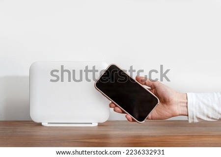 Female showing blank display on her phone with copy space for advertising internet provider services at home. Cropped shot of woman hand holding smartphone close to wi-fi router check connection speed Royalty-Free Stock Photo #2236332931