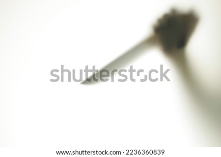 Blurred Shadow figure with a knife behind glass. Concept of serial killer, domestic violence