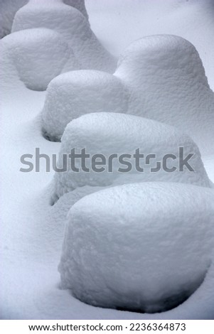 Fresh fluffy snow covered with a thick layer large stones. Abstract relief picture.