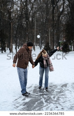 Winter couple activities. Winter Date Ideas to Cozy Up. Cold season dates for couples. Young couple in love waking, skating and having fun in winter snowy park.