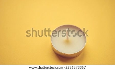 New round candle on yellow table.