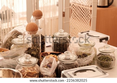 Herbal tea collection. Glass jars with lids. Master class on cooking, training. The hands of the participants are large against the background of jars and bowls with herbs. Ecological, clean.