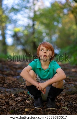 a boy of nine sits on a path in the woods alone