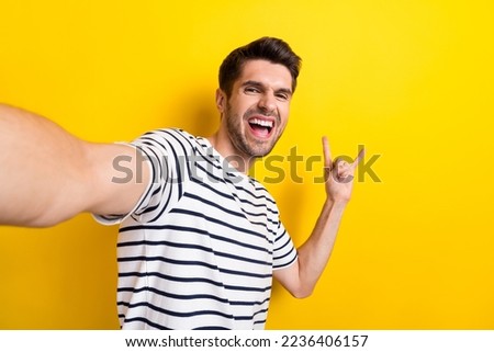 Portrait of careless childish person make selfie hand finegrs show heavy metal symbol isolated on yellow color background