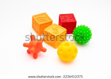 Three sensory balls in different warm colors and three silicone soft cubes on a white background. Tactile toys for the development of babies Royalty-Free Stock Photo #2236412375