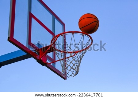 A basketball ball flies into a basket on an open basketball court. Basketball against the sky.