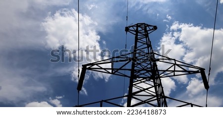 Electricity pylon (high voltage power line), black contour,  on the background of the cloudy sky
