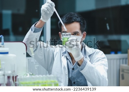 Scientist man is seriously doing research on the ingredients development of pharmaceutical and cosmetic products, using nanoparticles mixed in formulation test on beaker in the laboratory. Royalty-Free Stock Photo #2236439139