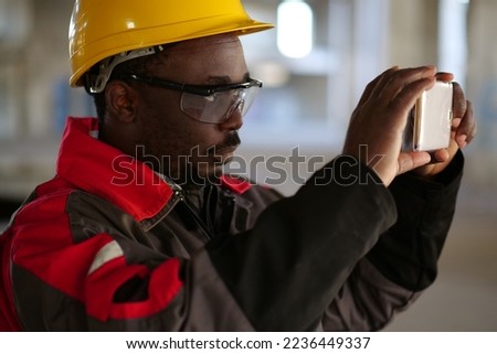 Worker taking photo on smartphone. African american worker records videos on smartphone. Manager of the works at construction site filming video