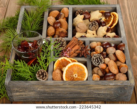Mulled wine, spices and nuts in a wooden box on brown background