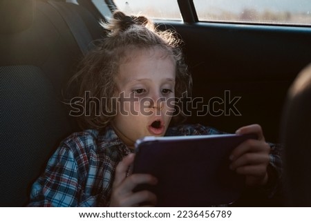 Excited boy watching a movie on technology tablet in car. Child using computer.