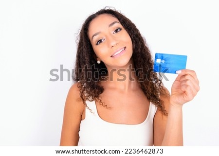 Close up photo of optimistic Beautiful teen girl with curly hair wearing white sport set over white background hold card