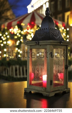 Small and bright lantern with the candle inside pictured at one of the tables at the Christmas Market in Riga, Latvia.