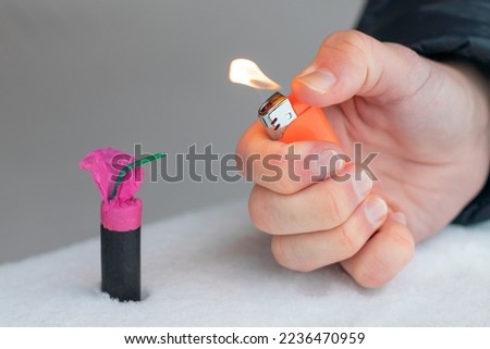 Guy Sets Fire to the Flash Noise Firecracker Outdoors in Winter at Daytime. Loud and Dangerous New Year's Entertainment. Hooliganism with Pyrotechnics. Noise of Petards in Public Places Royalty-Free Stock Photo #2236470959