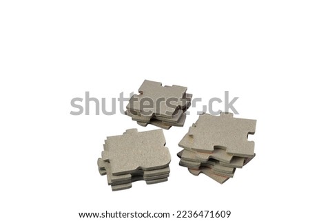 Three medium sized piles with puzzle pieces. Cardboard material. Close up and isolated on a white background.