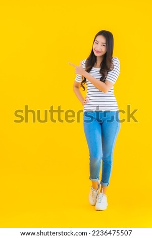 Portrait beautiful young asian woman smile happy with action on yellow isolated background