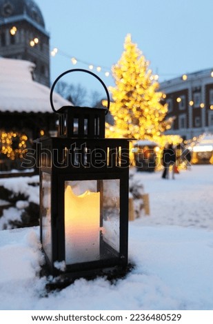 Small and bright lantern with the candle inside pictured at one of the tables at the Christmas Market in Riga, Latvia.