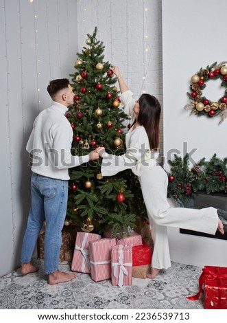 Couple decorating Christmas tree with star topper in room