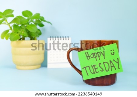 Welcome, hello and happy Tuesday concept. Selective focus of coffee cup with green paper note and written message.
