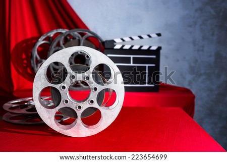 Cinema clapper and reel on the background of red curtain