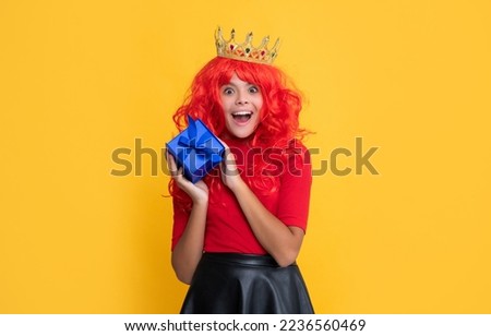 amazed child in princess crown with present box on yellow background