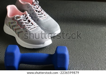 A blue barbell and grey sport shoes on the mattress. Indoor workout concept and healthy lifestyle. Sport equipment background.