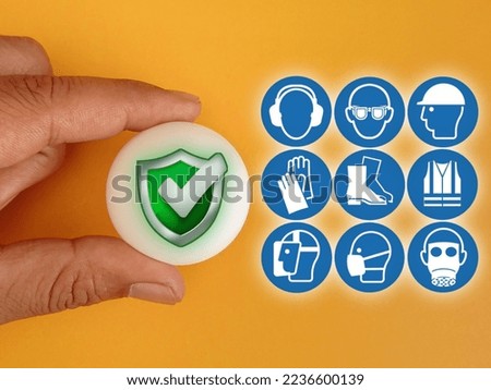 Hand holding white ball with Safety icon and workplace icons on orange background.Concept of workplace safety Or Safety at work.