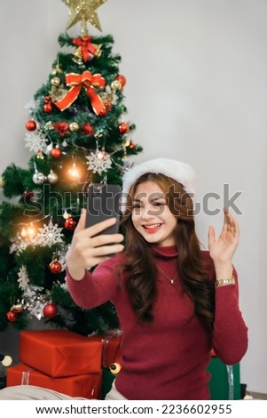 Young Asian woman poses with happy Christmas presents, Young woman celebrating Christmas holidays, Thanksgiving party in home living room.