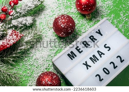 Light box surrounded by Christmas decorations with the words merry xmas