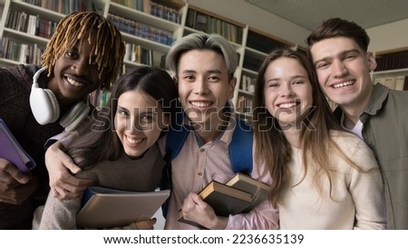 Happy young classmates team having fun in college, university library, taking group selfie portrait. Cheerful diverse student girls and guys looking at camera, smiling, laughing. Banner shot