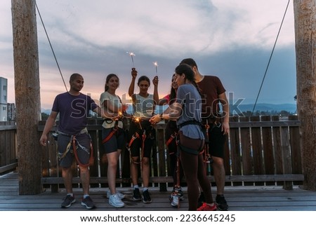 Young group of skilled rock climbers having fun and playing with sparkles with the sun setting in the background