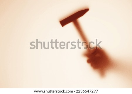 Blurred shadow of a hand with a hammer outside the window. The concept of robbery, murder