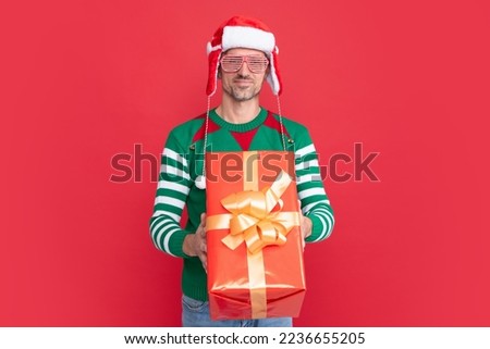 happy elf man in earflap santa claus hat. xmas guy in party glasses with present box
