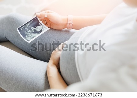 Pregnant woman with ultrasound image with sunlight. Concept love for unborn child.