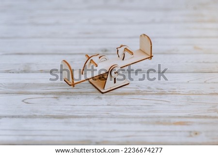 Small, miniature wooden homemade children's swing for balance, a toy from the playground constructor set, close-up in the studio. Photography, design, decor, game.